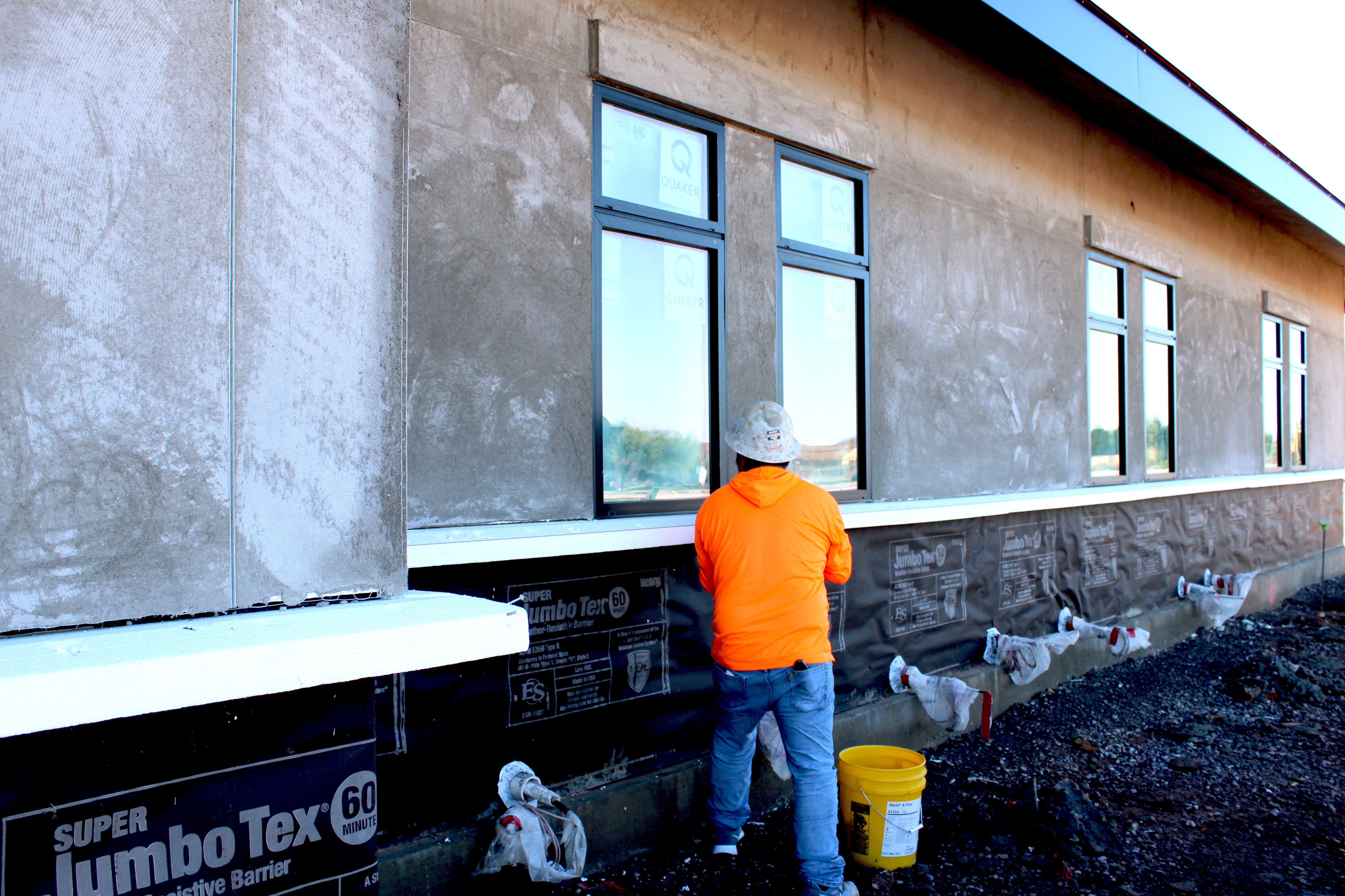 A worker applying stucco to an exterior wall.